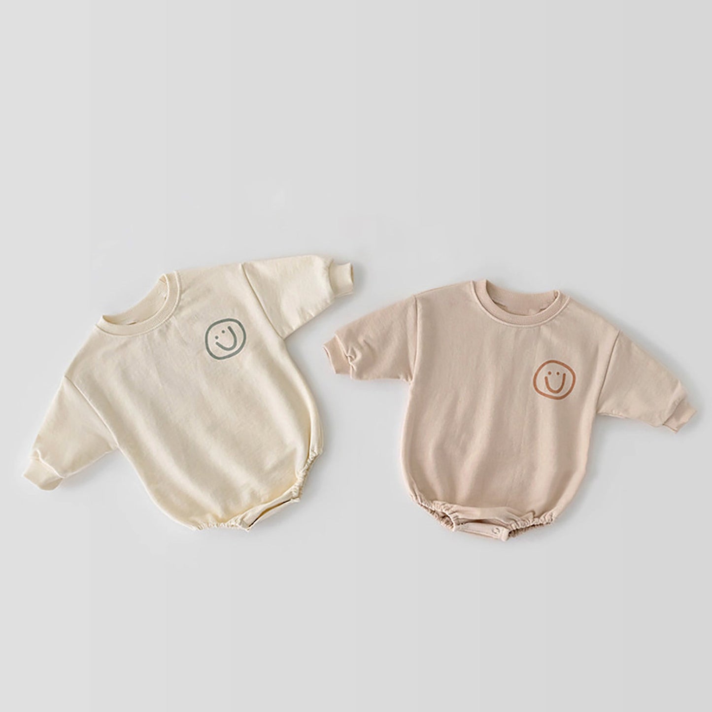 Beige Baby sweatshirt style romper and Rosey pink romper both the same style with smiley faces on the corner